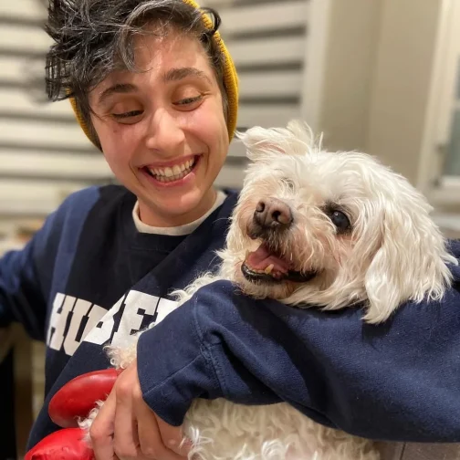 Zack smiling and holding a fluffy white dog