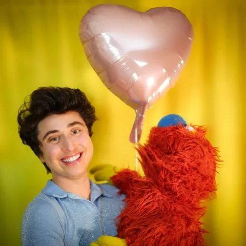 Zack & Ticklemuff holding a heart-shaped balloon against a yellow background